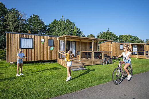 Modernos Mobil-homes de madera con terraza, niños jugando en camping CAPFUN Ponderosa en Ulicoten.