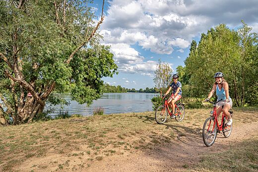 Paseo en bicicleta junto al lago en el camping CAPFUN Les Portes du Beaujolais en Anse (69).