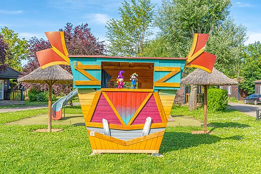 Estructura de juegos colorida con marionetas y tobogán en el camping CAPFUN Les Portes du Beaujolais en Anse (69).