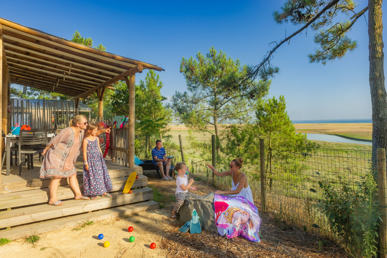 Familia en terraza de Mobil-home con vista mar en camping CAPFUN Prises en La TRANCHE SUR MER (85).
