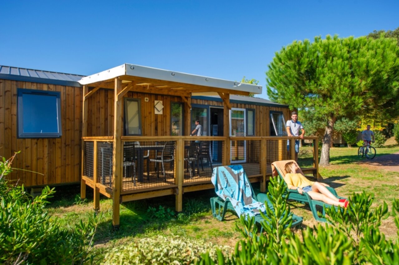 Mobil-home de madera con terraza cubierta y tumbonas en el camping CAPFUN Quatre Vents d'Ol�ron en St Georges d�Ol�ron (17).