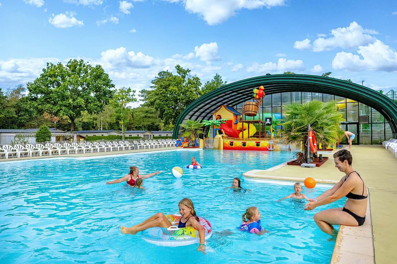 Piscina exterior con juegos acu�ticos y familias en el camping CAPFUN Rakelbos en Westelbeers.