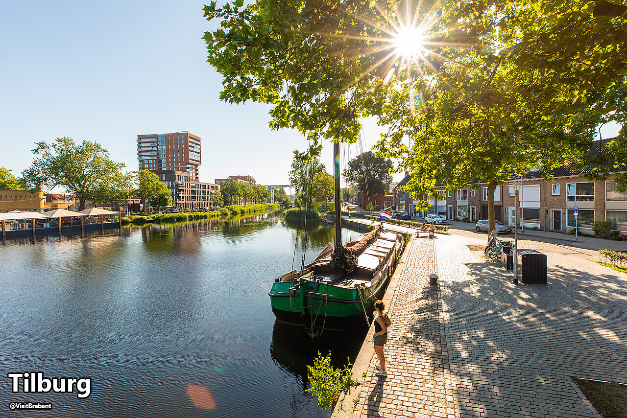 Canal con barco tradicional y edificios modernos en Tilburg, Brabante Septentrional.