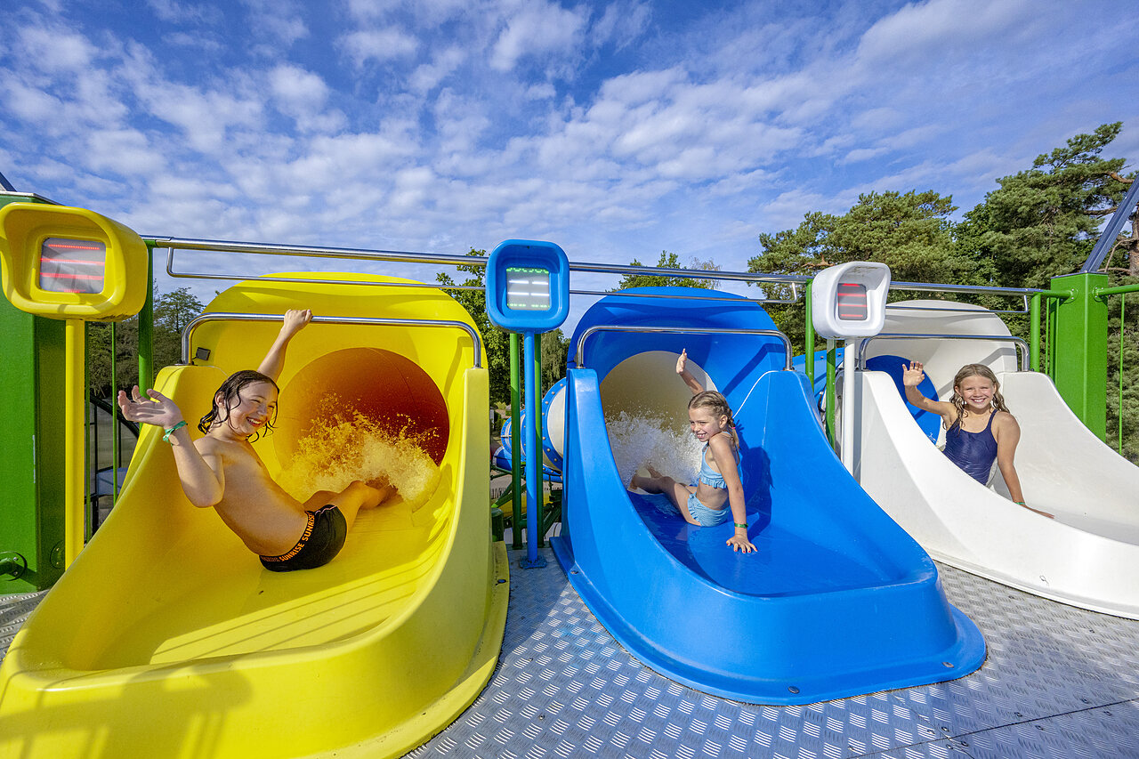 Ni�os disfrutando de toboganes acu�ticos coloridos en el camping CAPFUN Rakelbos en Westelbeers.