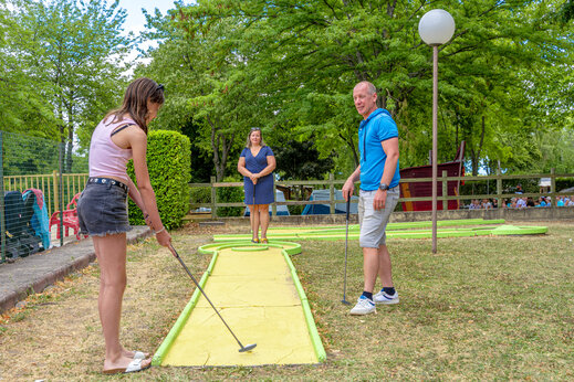 Familia jugando al minigolf en un campo exterior en el camping CAPFUN Ranch des Volcans en Chatel-Guyon (63).