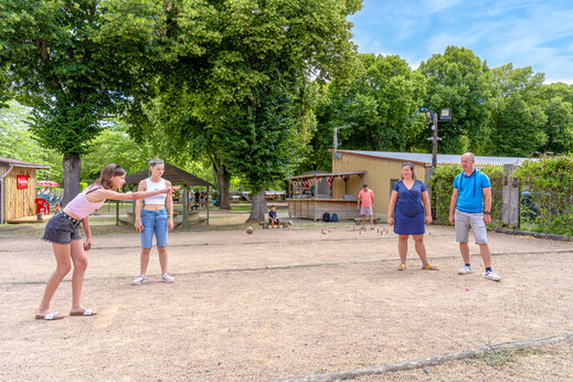 J�venes y adultos jugando a la petanca en una cancha deportiva en el camping CAPFUN Ranch des Volcans en Chatel-Guyon (63).