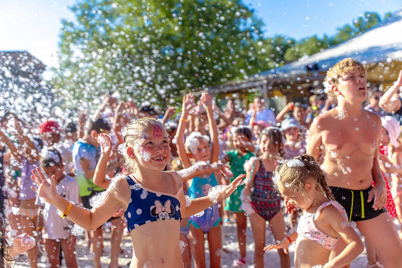Ni�os felices disfrutando de una fiesta de espuma animada en el camping CAPFUN R�gni�re en VILLETTE D'ANTHON (38).