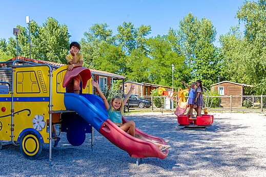 Zona de juegos colorida con tobogán y niños sonriendo en el camping CAPFUN Régnière en VILLETTE D'ANTHON (38).