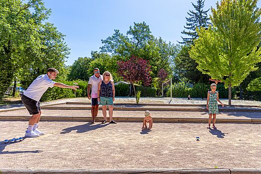 Familia jugando a la petanca en cancha dedicada en camping CAPFUN Régnière en VILLETTE D'ANTHON (38).