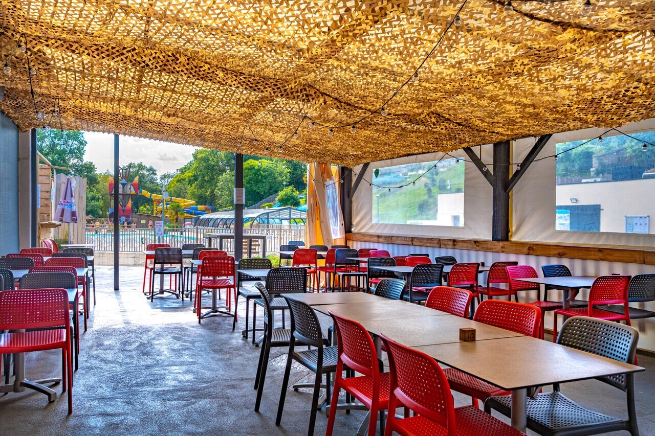Terraza restaurante sombreada, mesas, sillas, piscina, camping CAPFUN La Rivi�re en Valence-en-Poitou (86).