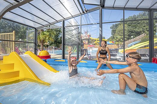 Piscina cubierta, tobogán, niños en el camping CAPFUN La Rivière en Valence-en-Poitou (86).