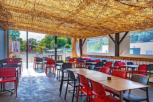 Zona de restaurante exterior sombreada con mesas y sillas en el camping CAPFUN La Rivi�re en Valence-en-Poitou (86).