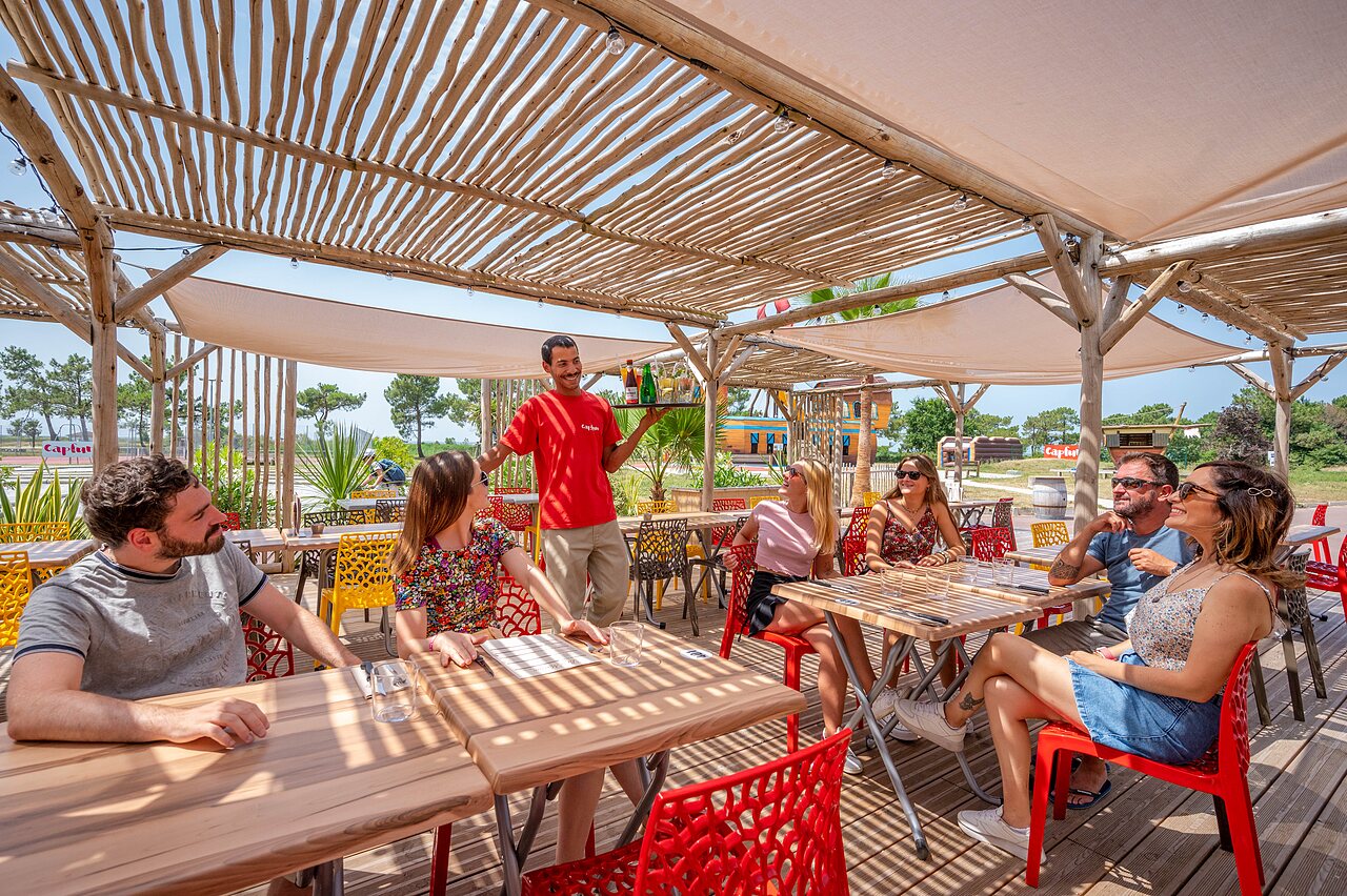 Terraza restaurante y bar sombreada, clientes servidos en el camping CAPFUN Roumingue en LANTON (33).