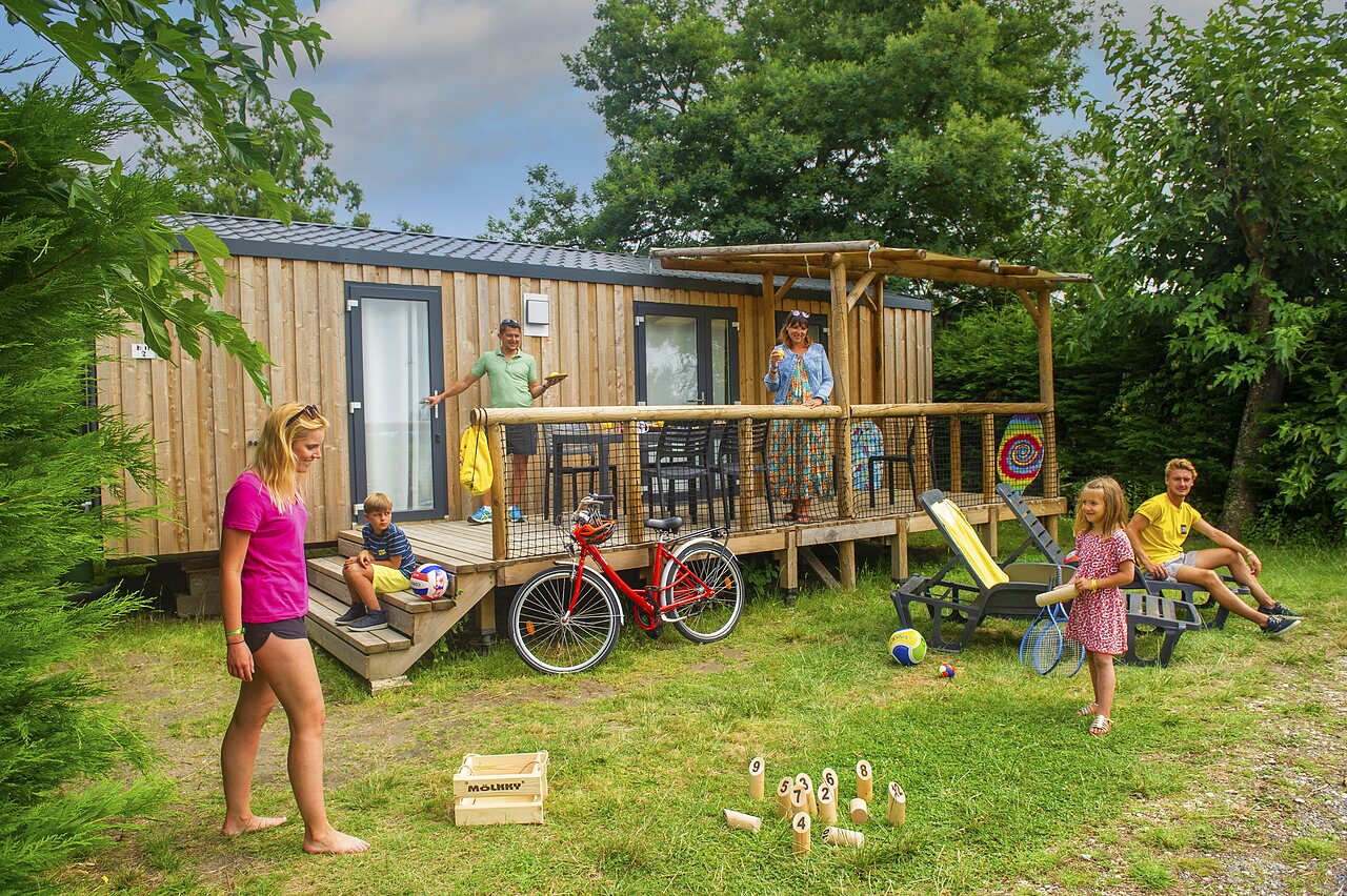 Familia disfrutando de un Mobil-home moderno con terraza y juegos en el camping CAPFUN Roumingue en LANTON (33).