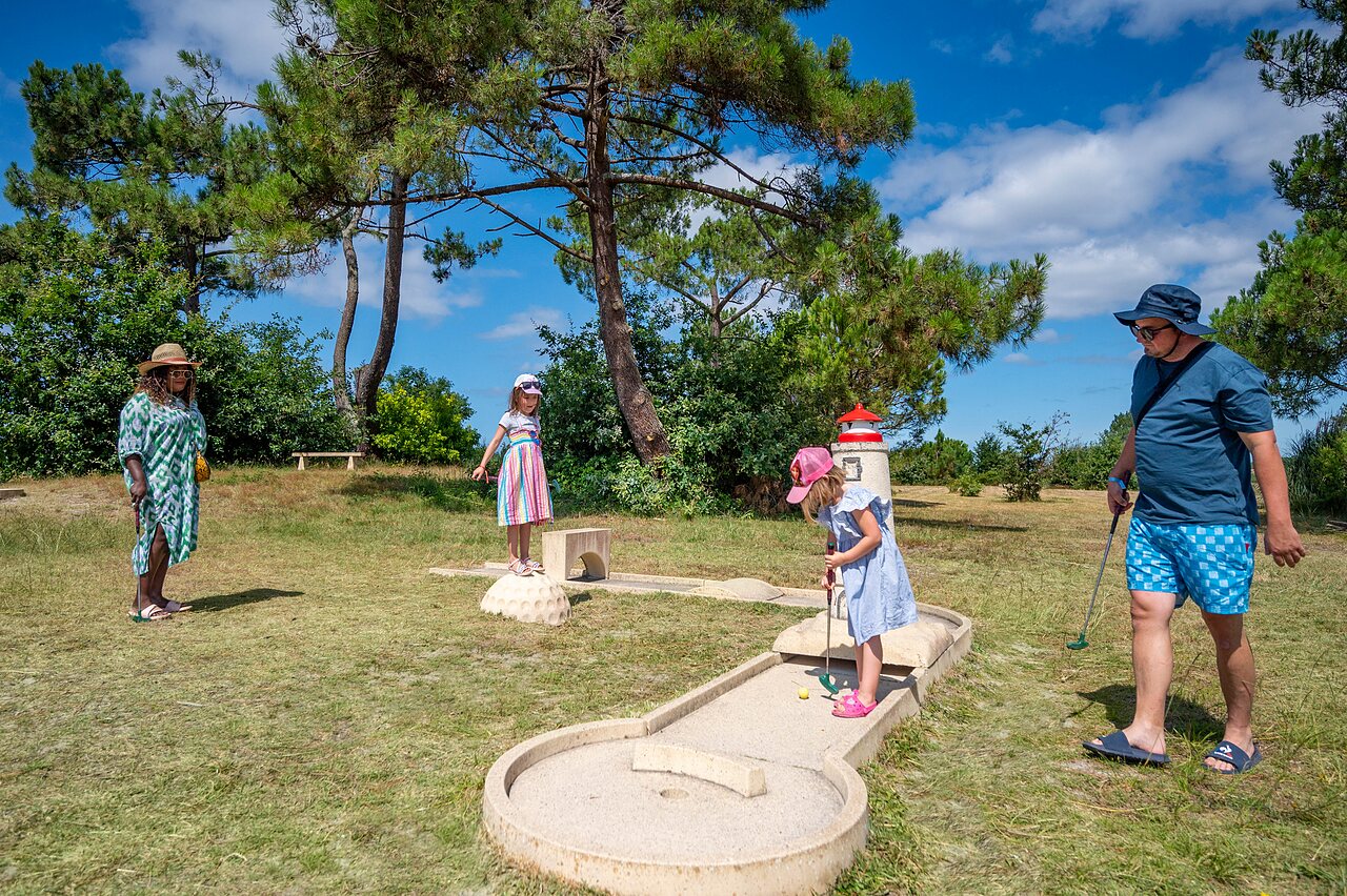 Familia jugando al minigolf con campo tem�tico en el camping CAPFUN Roumingue en LANTON (33).