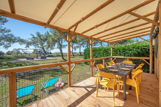 Terraza cubierta de Mobil-home con mesa y sillas amarillas en CAPFUN Roumingue.