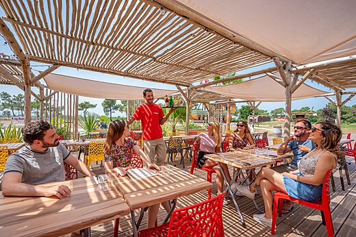 Terraza de restaurante con camarero sirviendo bebidas en camping CAPFUN Roumingue en LANTON (33)
