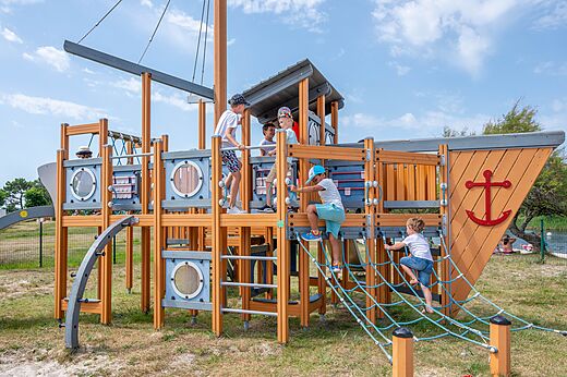 Zona de juegos con forma de barco y niños en el camping CAPFUN Roumingue en LANTON (33).