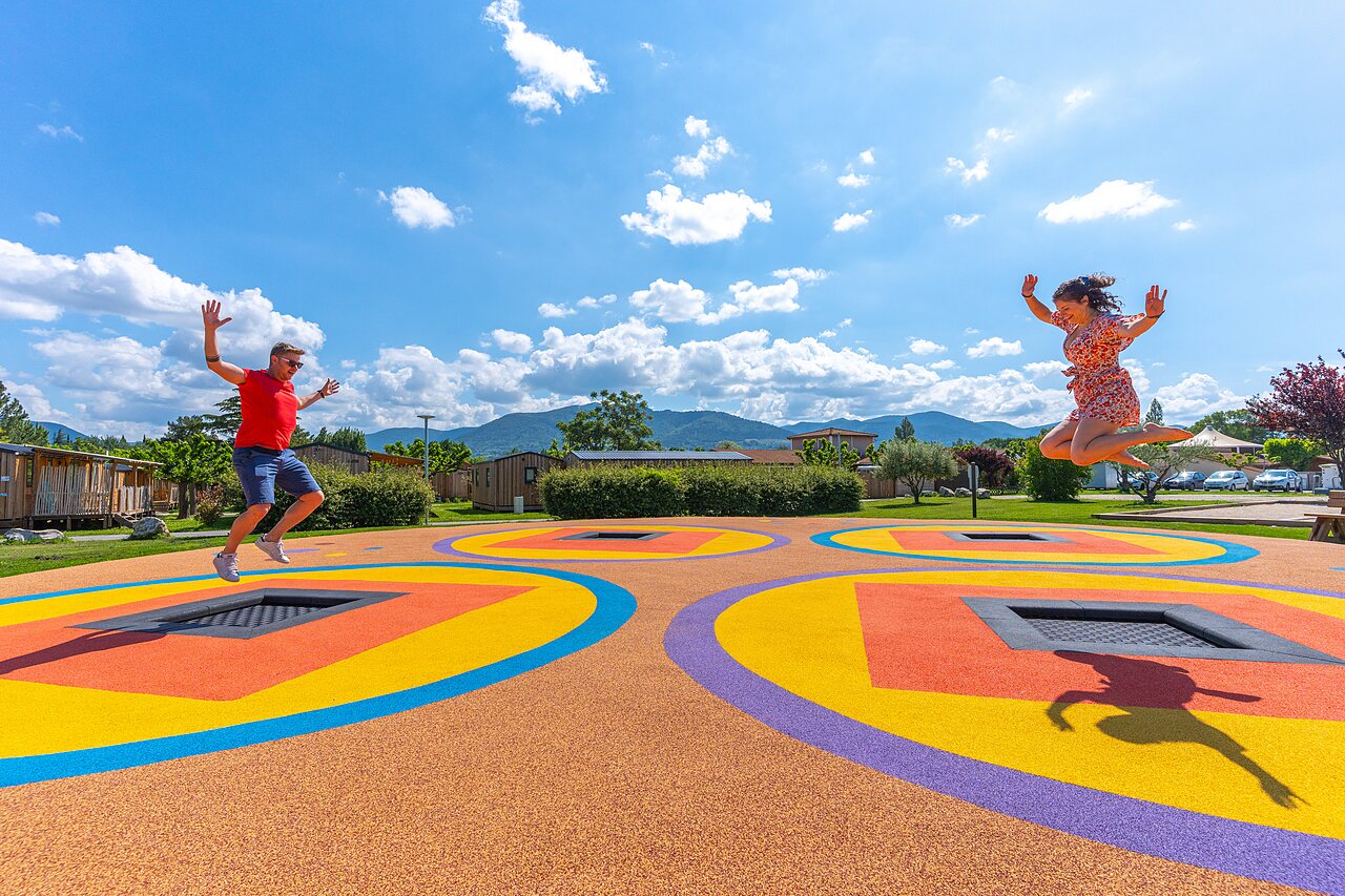Zona de juegos con trampolines integrados y personas saltando en el camping CAPFUN Sagittaire en VINSOBRES (26)