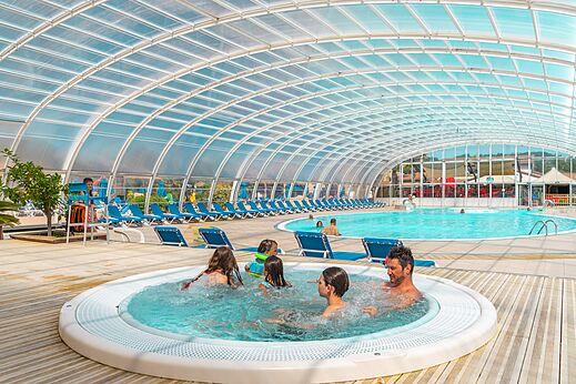 Piscina cubierta con jacuzzi y familia en el camping CAPFUN Sagittaire en VINSOBRES (26).