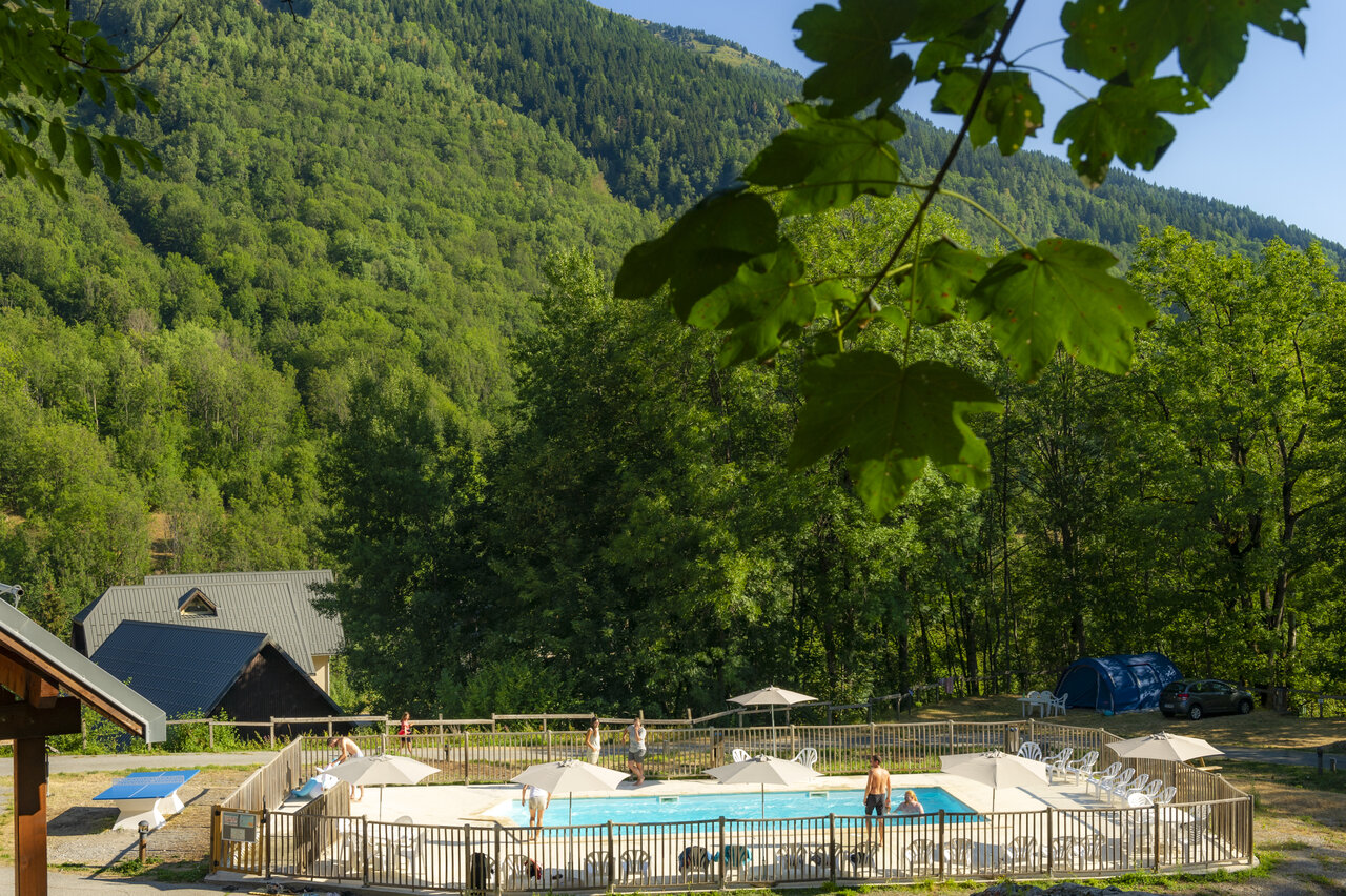 Piscina exterior con sombrillas en el camping CAPFUN Saint Colomban des Villards.