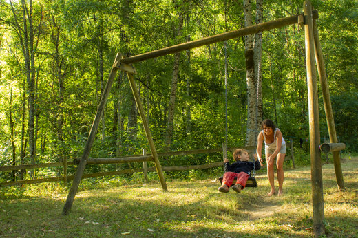 Ni�o en columpio de madera con mujer en camping CAPFUN Saint Colomban en Saint Colomban des Villards (73).