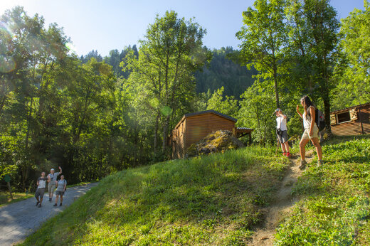 Senderistas en camino arbolado con Mobil-homes en camping CAPFUN Saint Colomban en Saint Colomban des Villards (73).