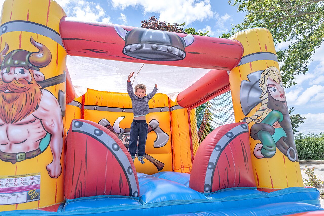 Castillo hinchable vikingo, ni�o saltando, en el camping CAPFUN Saint Laurent.