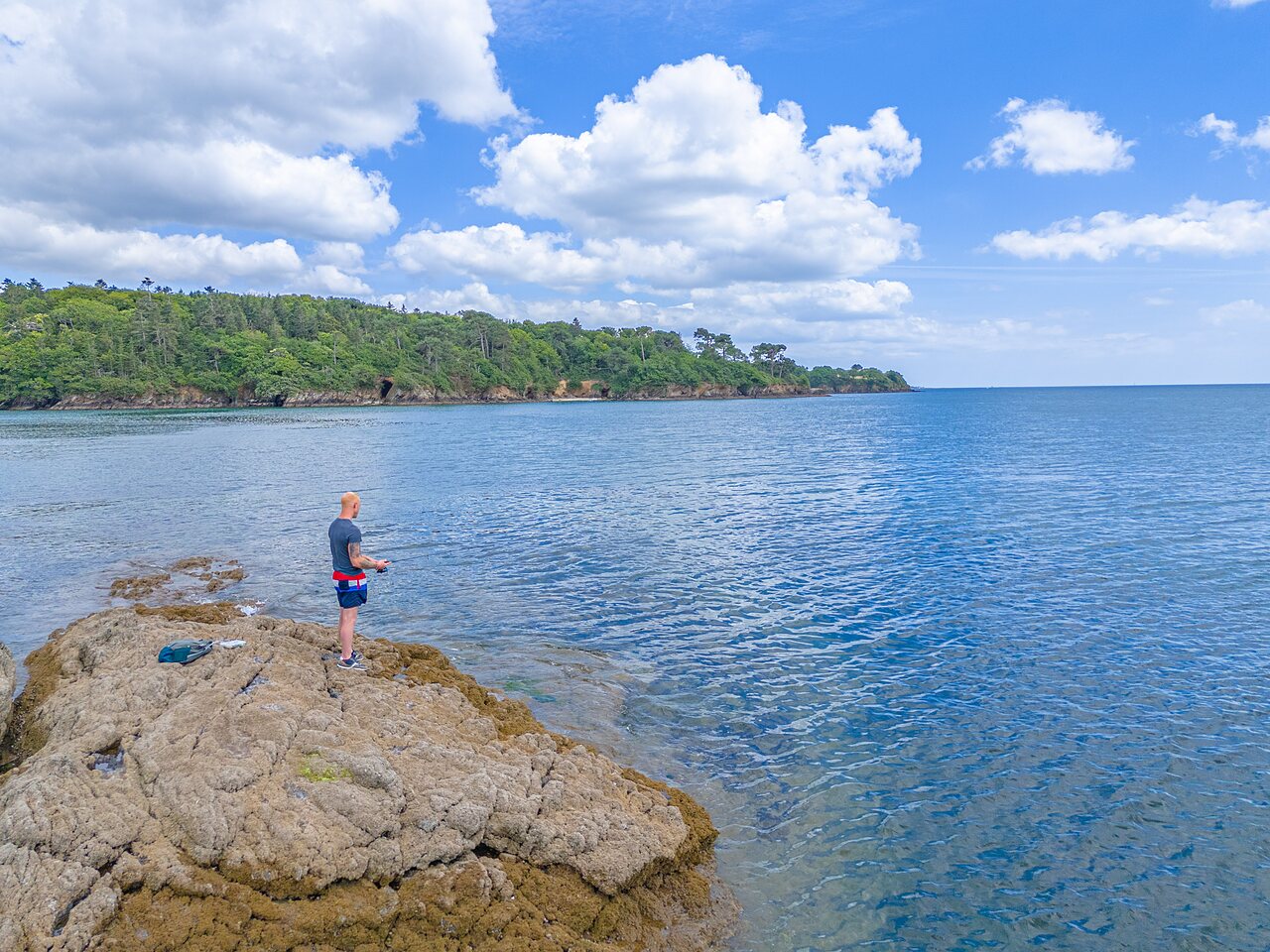 Pescador en las rocas junto al mar en el camping CAPFUN Saint Laurent en LA FORET FOUESNANT (29).