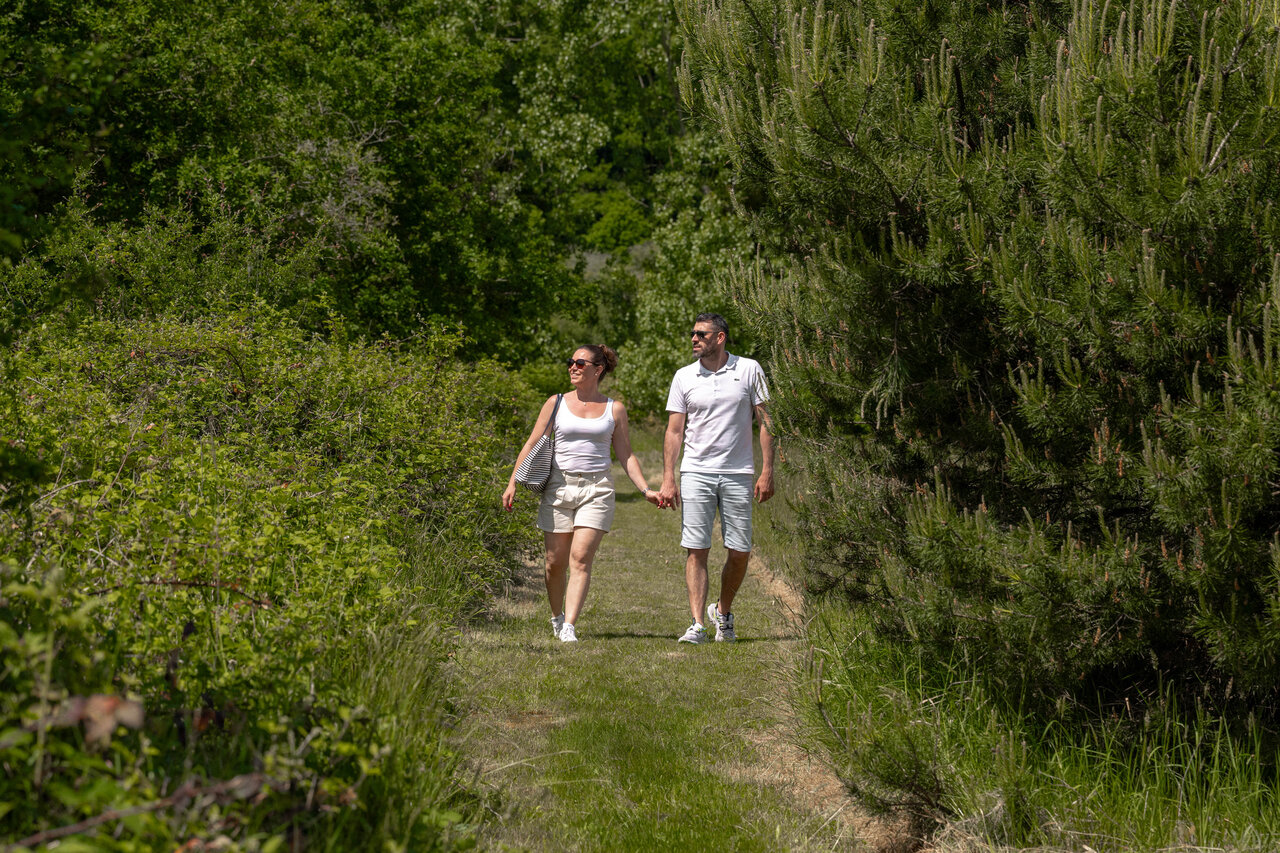 Pareja caminando por sendero natural verde en camping CLICOCHIC en Cheverny.
