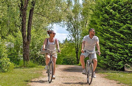 Pareja en bicicleta por sendero verde en camping CLICOCHIC Les Saules de Cheverny.
