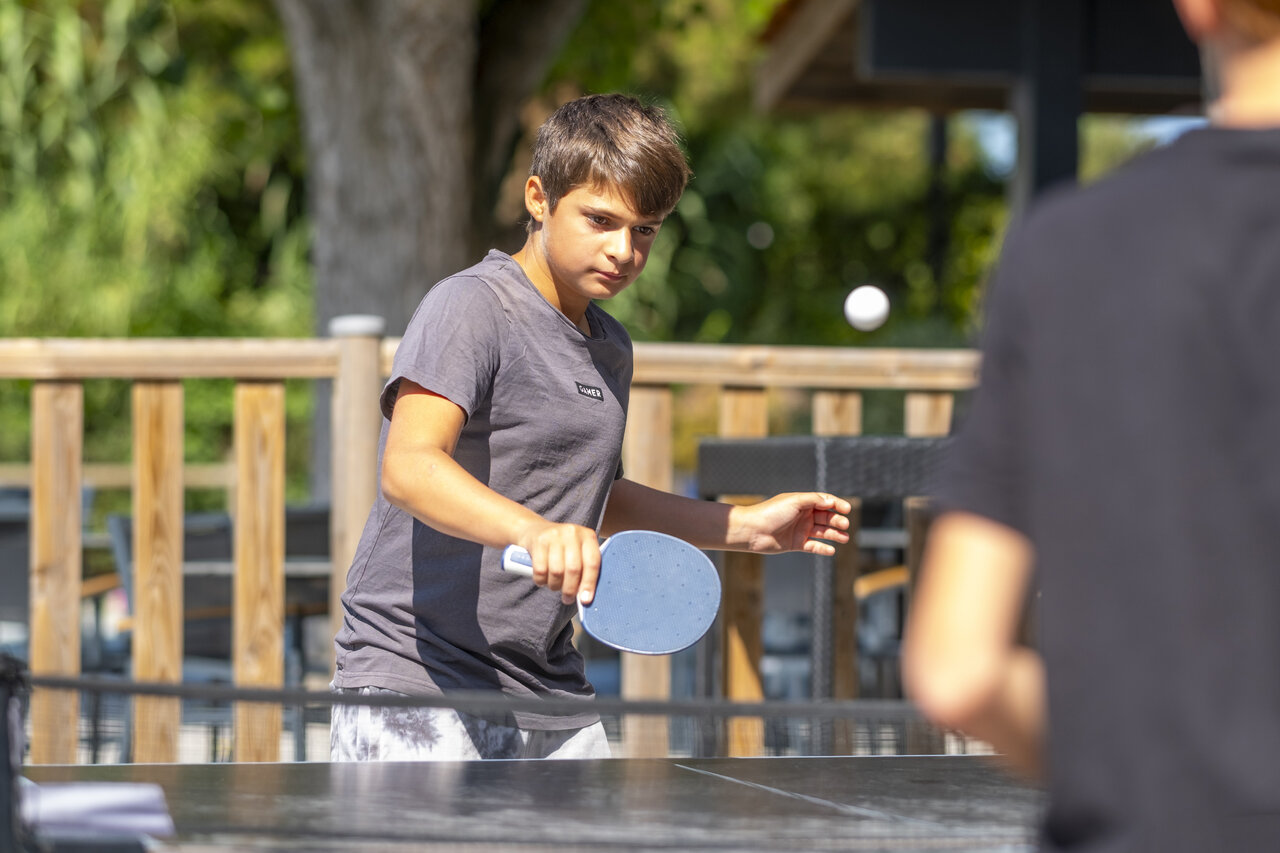 Joven jugando al tenis de mesa al aire libre en el camping CLICOCHIC Seuli�res en Saint-Denis-d'Ol�ron (17).