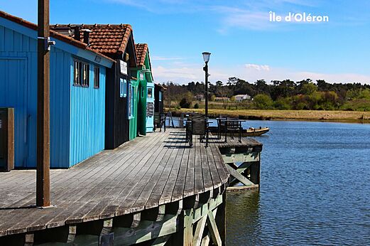 Cabañas ostrícolas coloridas sobre pilotes y terraza junto al agua, Isla de Oléron.