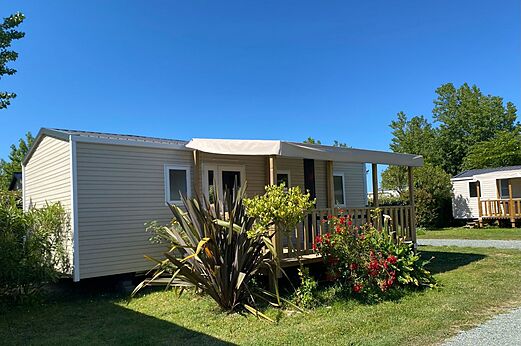 Mobil-home moderno con terraza cubierta y jardín florido en el camping CLICOCHIC Seulières en Saint-Denis-d'Oléron (17).