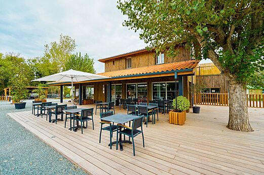 Terraza de restaurante con mesas y sombrilla en CLICOCHIC Seulières Saint-Denis-d'Oléron.