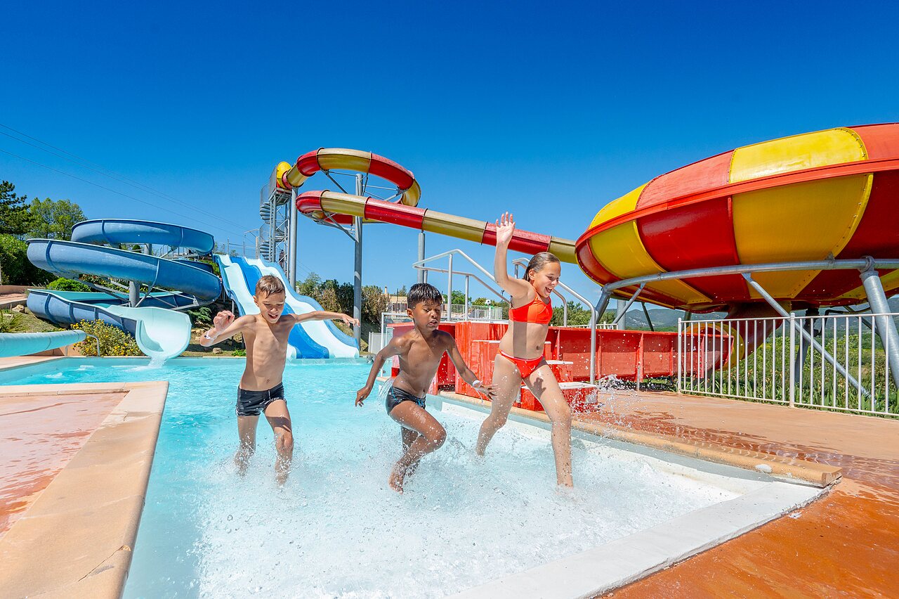 Ni�os jugando en la piscina con toboganes gigantes en el camping VAGUES OCEANES Soleil de Provence en Saint-Romain-en-Viennois.