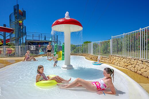Zona de juegos acuáticos con seta rociadora y niños en el camping VAGUES OCEANES Soleil de Provence en Saint-Romain-en-Viennois (84).