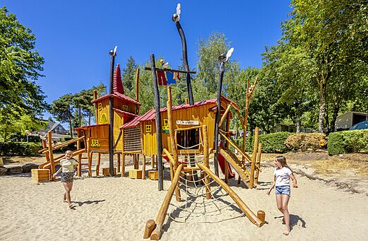 Gran parque infantil de madera con cabañas y toboganes en el camping CLICOCHIC Soleil Levant en Canet-de-Salars (12).