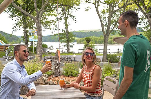 Clientes sonrientes disfrutando bebidas refrescantes en la terraza del bar en el camping CLICOCHIC Soleil Levant en Canet-de-Salars (12).