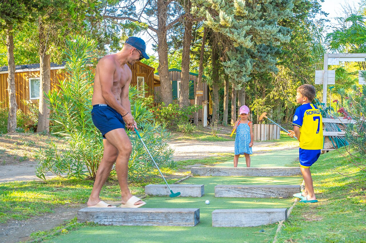 Familia jugando minigolf cerca de Mobil-homes en el camping CAPFUN Soubeyranne en REMOULINS (30).