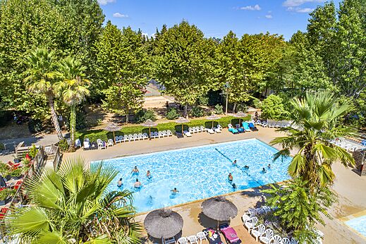 Piscina exterior con bañistas y sillas en el camping CAPFUN Soubeyranne en REMOULINS (30).