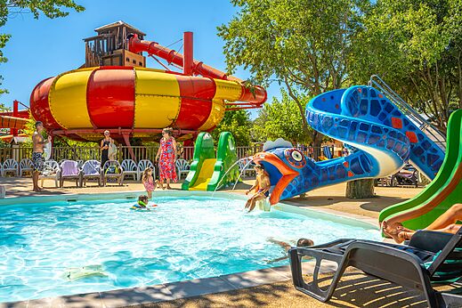 Toboganes acuáticos coloridos y piscina con niños jugando en el camping CAPFUN Soubeyranne en REMOULINS (30).