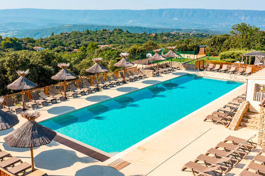 Piscina exterior con sillas y sombrillas en el camping CLICOCHIC Les Sources de Gordes en GORDES (84).