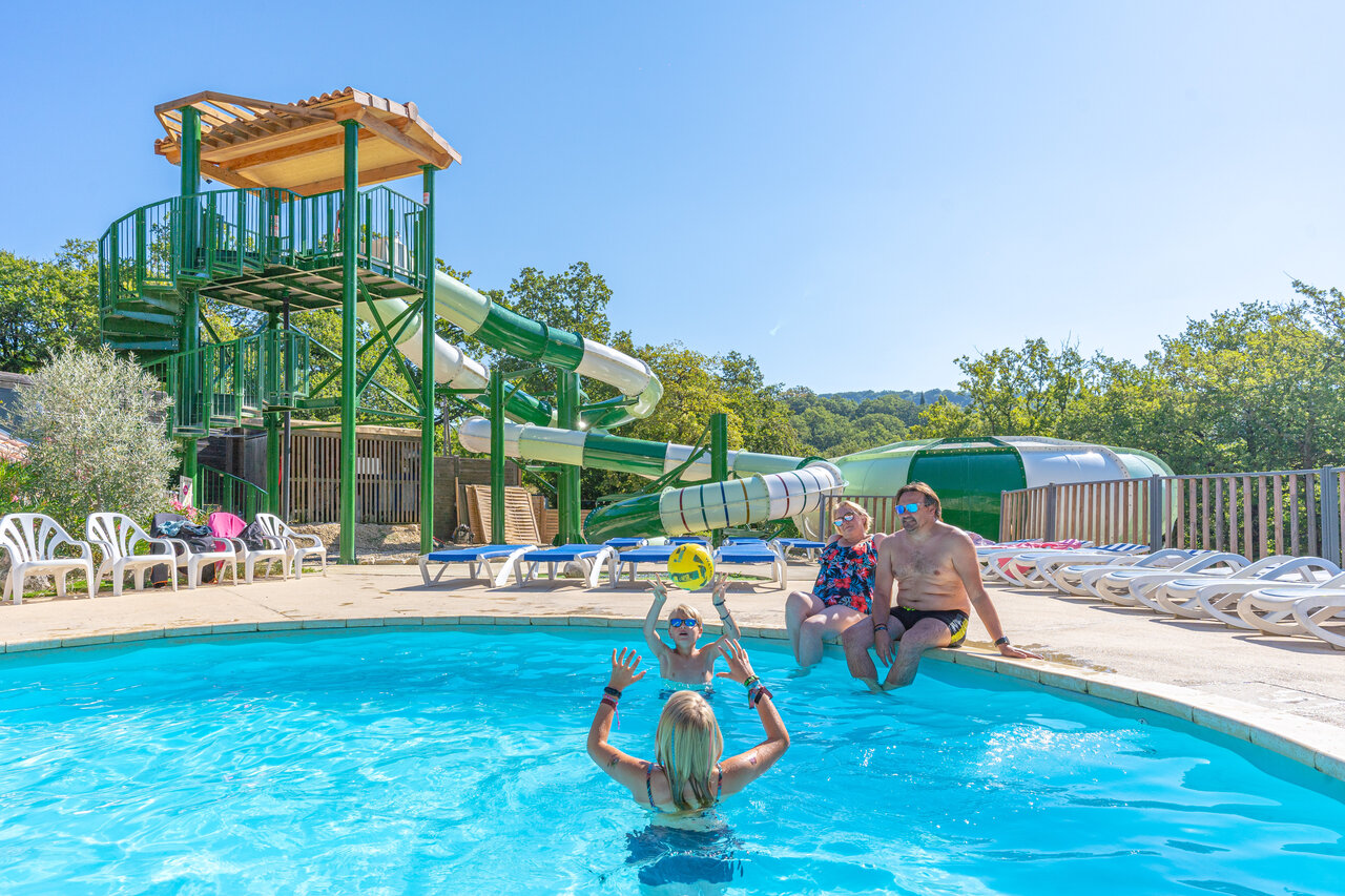 Familia jugando en la piscina con toboganes gigantes en el camping CLICOCHIC Source du Jabron en Comps (26).