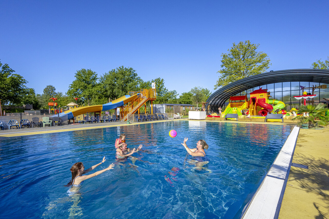 Familia jugando en la piscina con toboganes en el camping CAPFUN De Sprookjescamping en Rheeze.