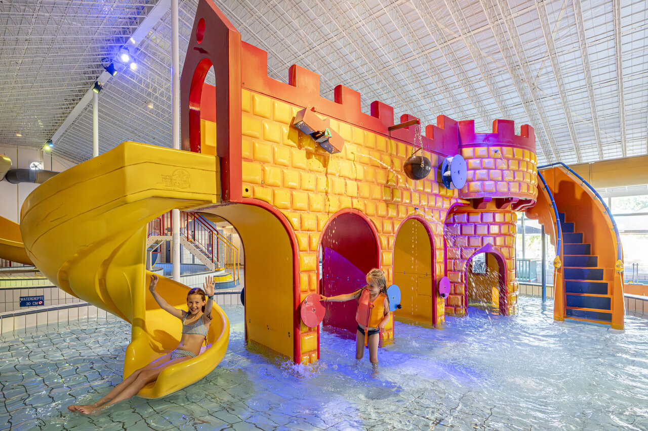 Zona de juegos acu�ticos cubierta con tobog�n y castillo en el camping CAPFUN De Sprookjescamping en Rheeze.