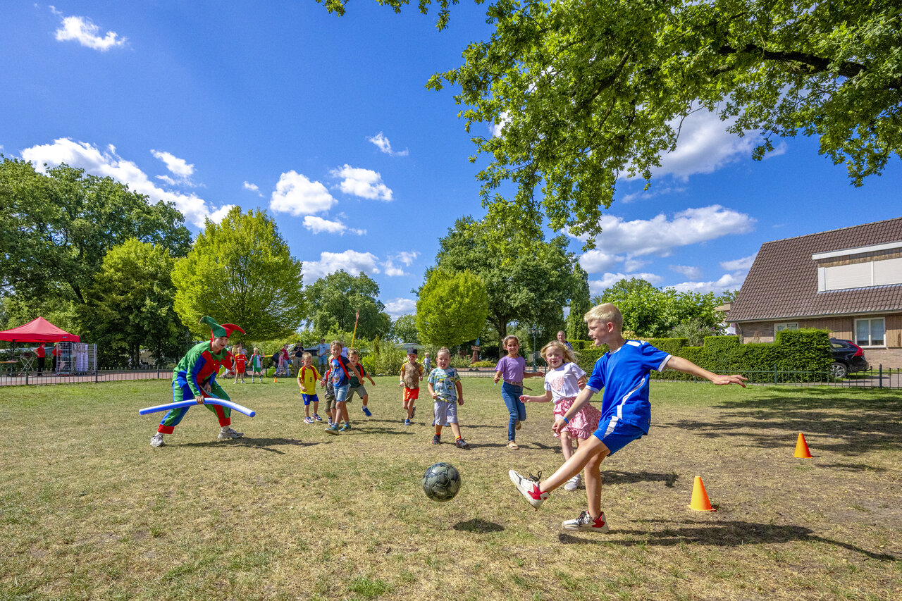 Ni�os jugando al f�tbol con animador disfrazado en el camping CAPFUN De Sprookjescamping en Rheeze.
