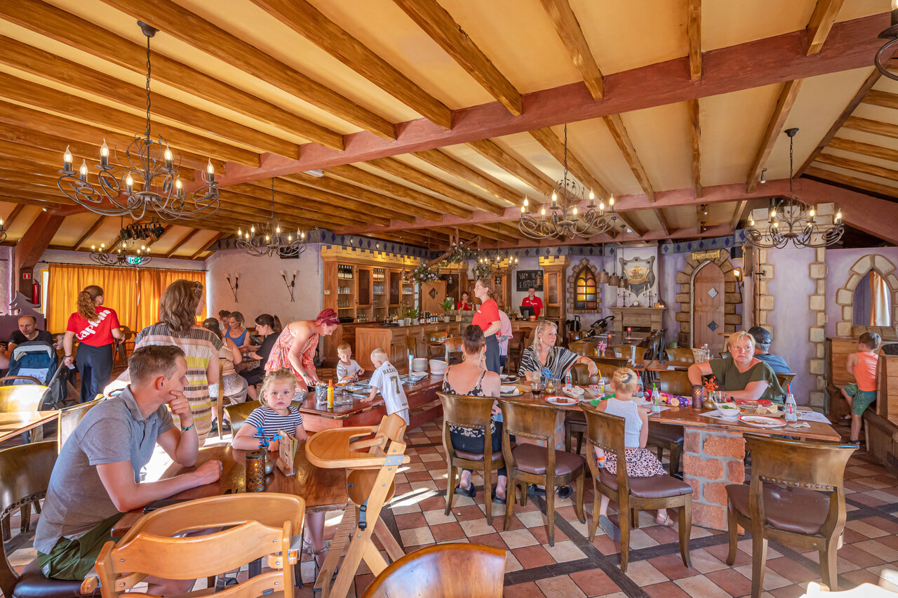 Restaurante familiar animado con mesas y clientes en el camping CAPFUN De Sprookjescamping en Rheeze.