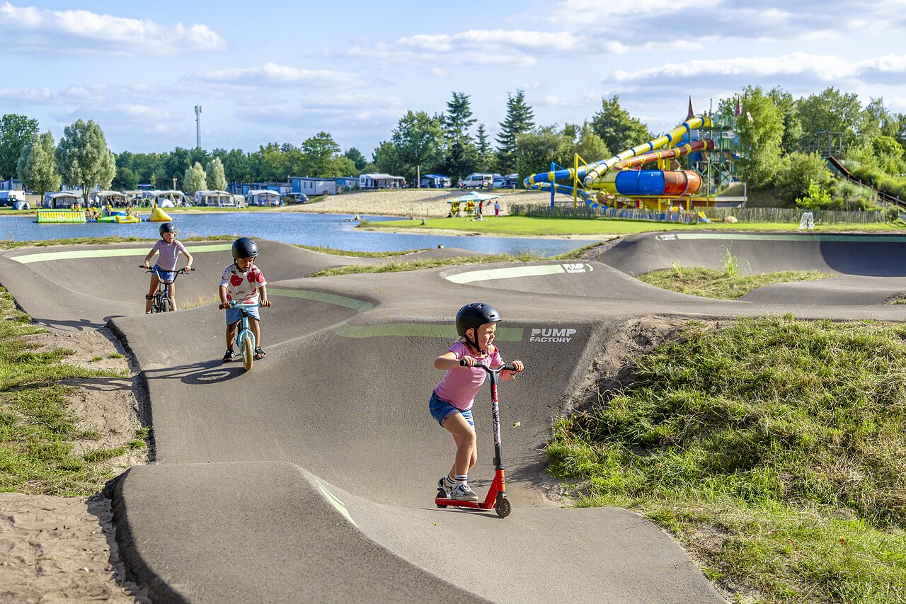 Ni�os en pump track con bicicletas y patinete en CAPFUN Vakantiepark het Stoetenslagh.