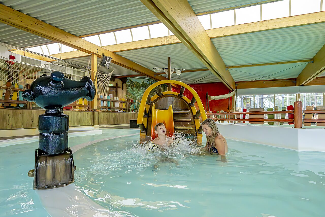 Ni�o y mujer riendo en tobog�n acu�tico pirata en piscina cubierta en camping CAPFUN Vakantiepark Capfun het Stoetenslagh en Rheezerveen.
